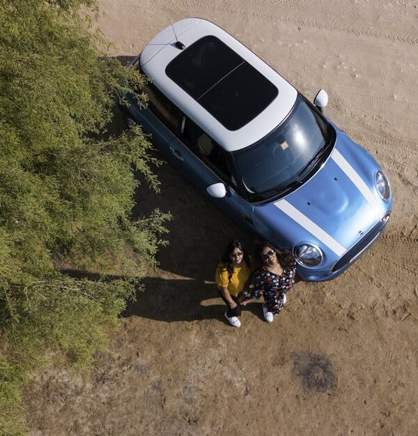 Two Woman Standing Beside Blue Mini Cooper