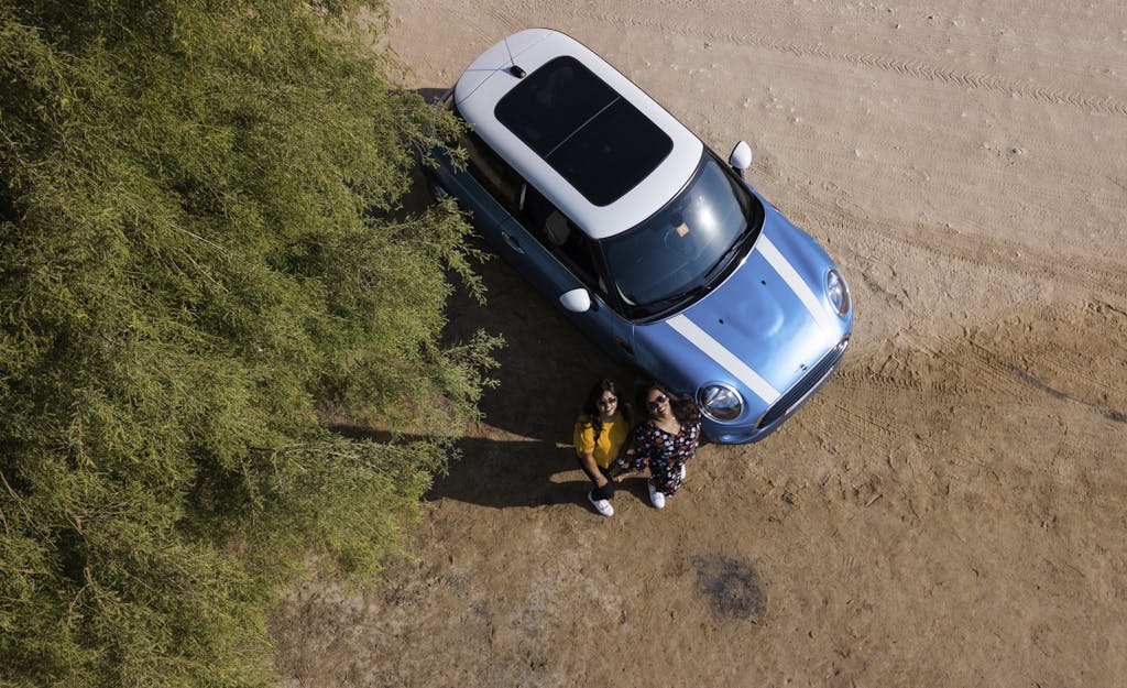 Two Woman Standing Beside Blue Mini Cooper