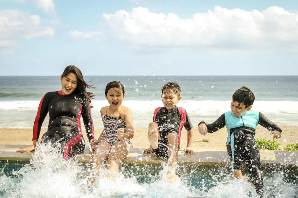 A family having fun splashing water near the seashore on a sunny day in Bali, Indonesia.