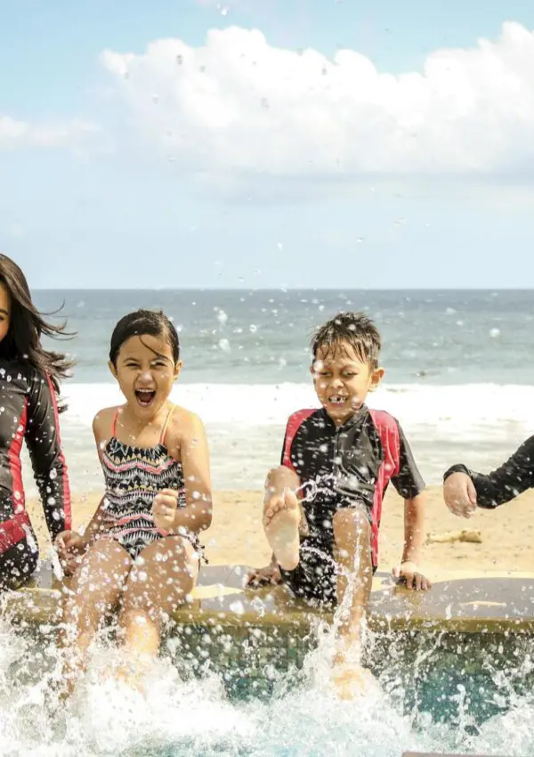 A family having fun splashing water near the seashore on a sunny day in Bali, Indonesia.