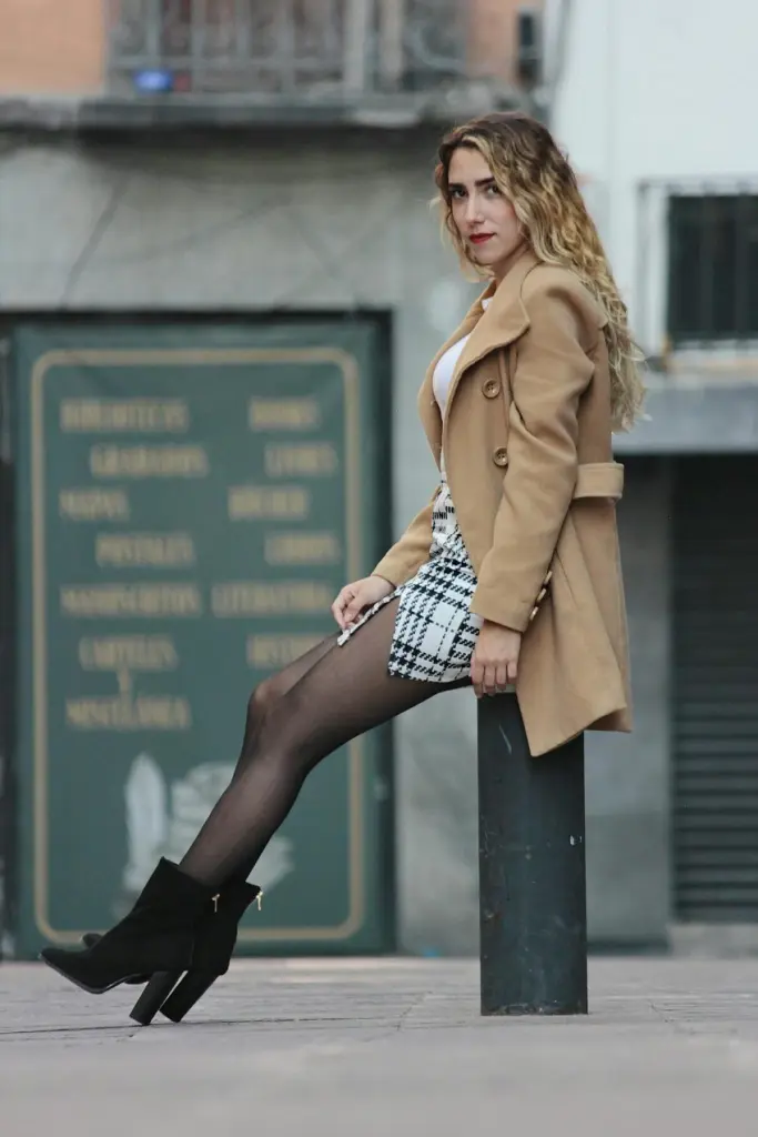 Elegant woman in winter fashion poses against a cityscape , highlighting urban style.